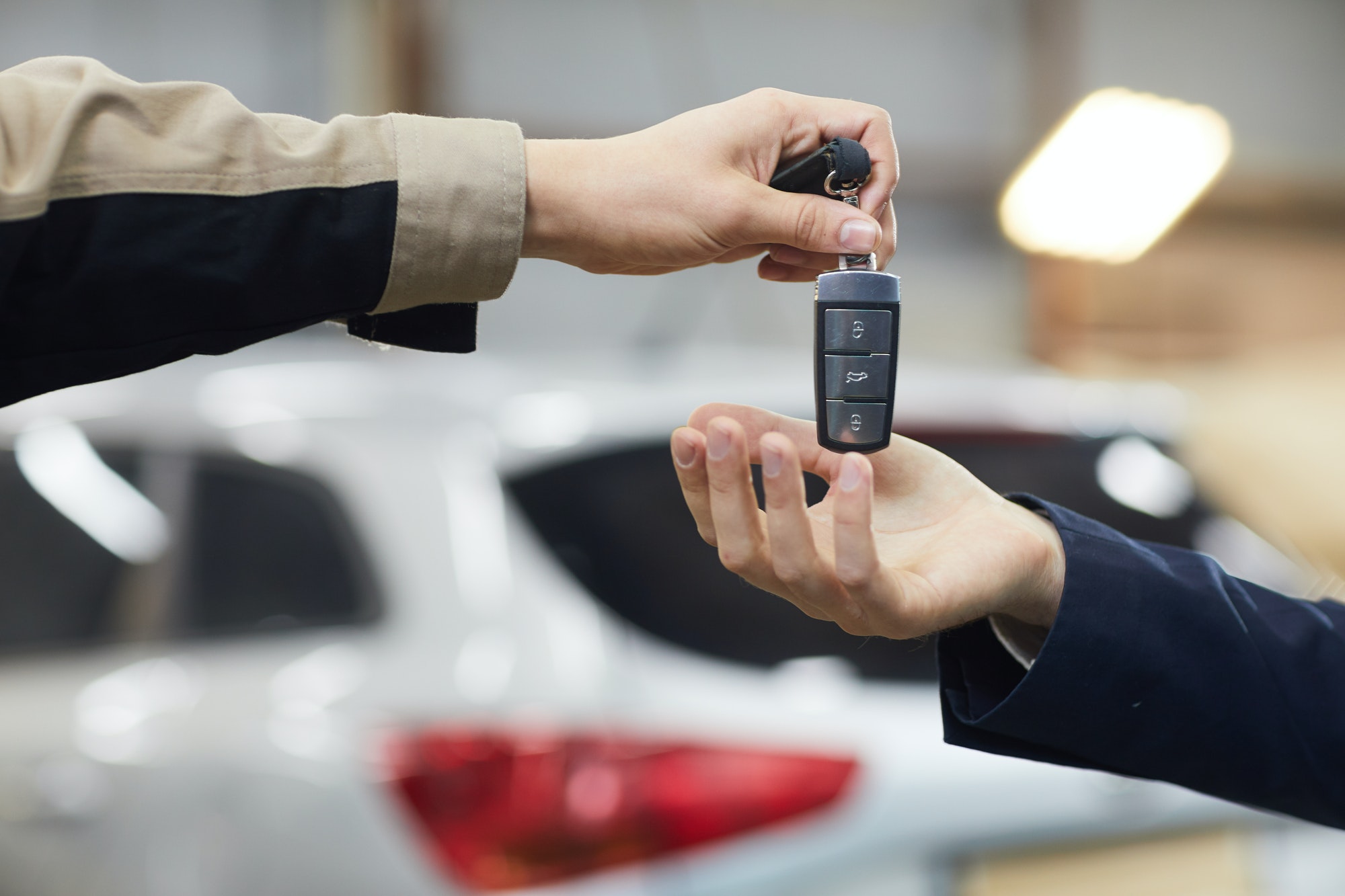 Gros plan horizontal de la main d'un mécanicien automobile donnant les clés de la voiture à un propriétaire méconnaissable, espace de copie
