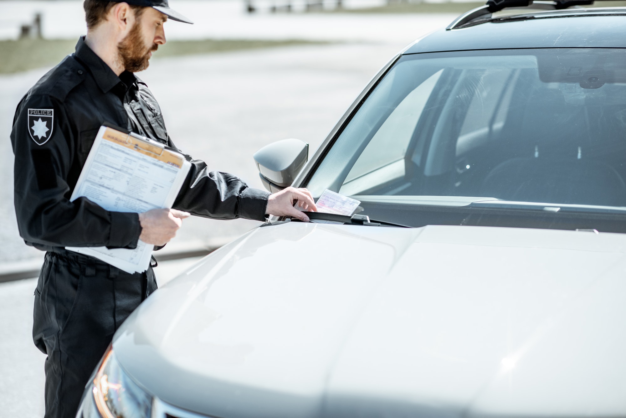 Policier infligeant une amende pour stationnement inapproprié sur le pare-brise de la voiture au bord de la route