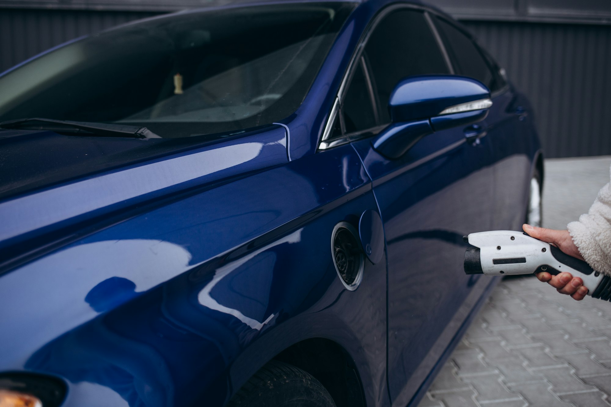 La main humaine tient la charge de voiture électrique connectée à la voiture électrique.