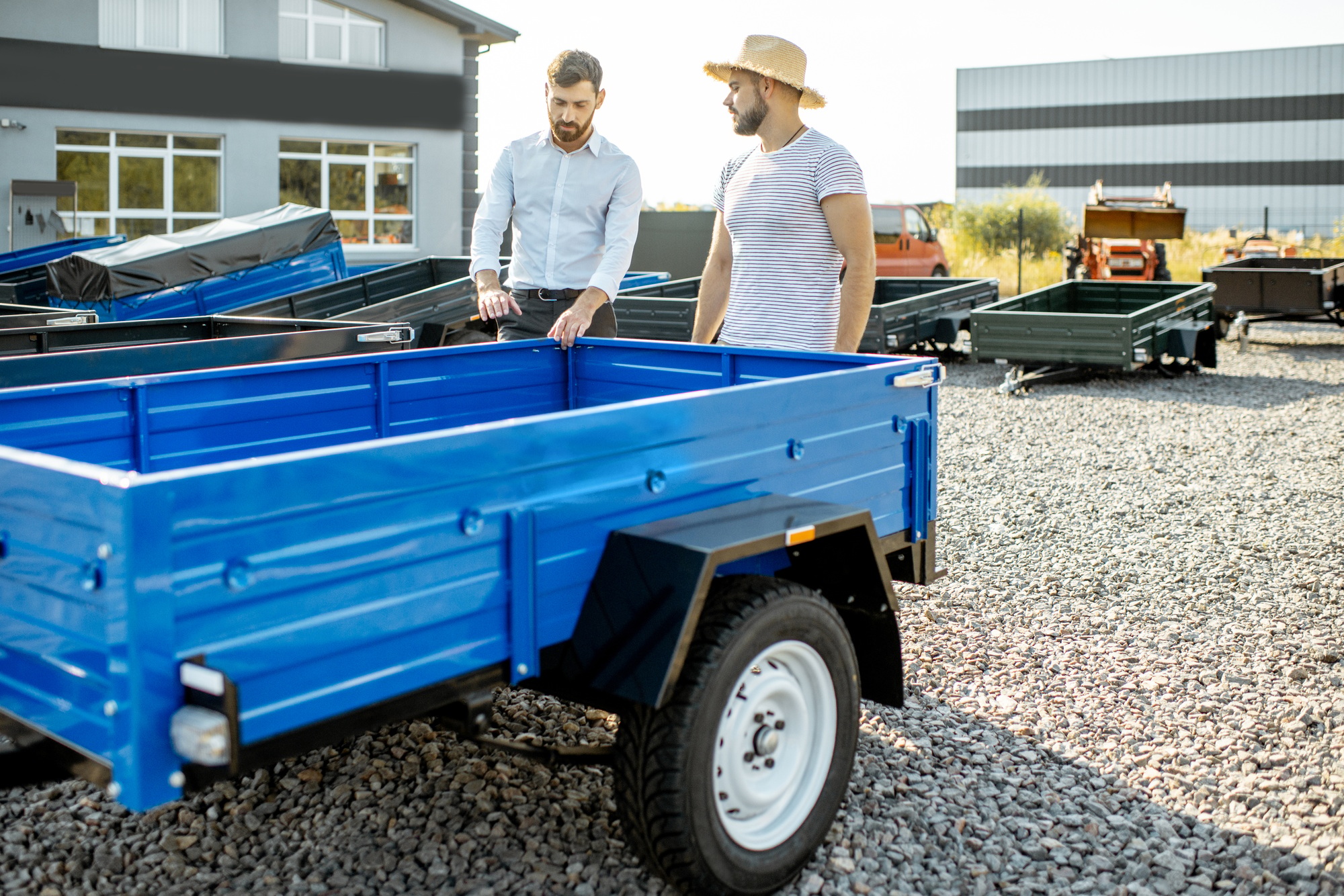 Agronome avec Salesman Choisant une nouvelle remorque de camion de ferme, debout sur le terrain ouvert de la boutique agricole