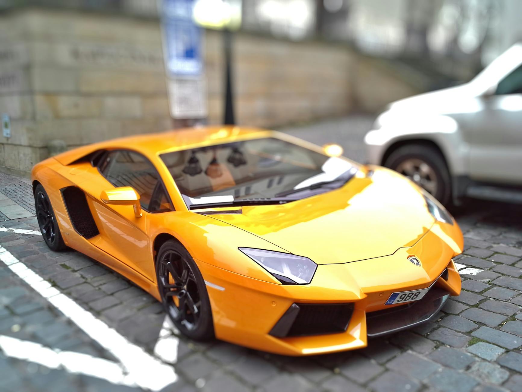 Voiture de sport jaune sur une rue pavée, présentant un design élégant et une couleur vibrante.