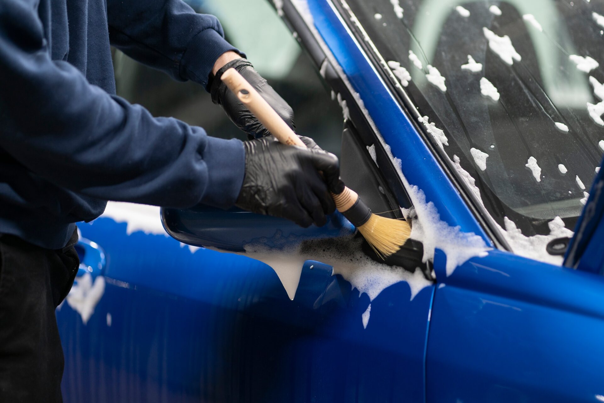 Atelier de détail de la voiture, homme travaillant avec Brush, nettoyage de la voiture