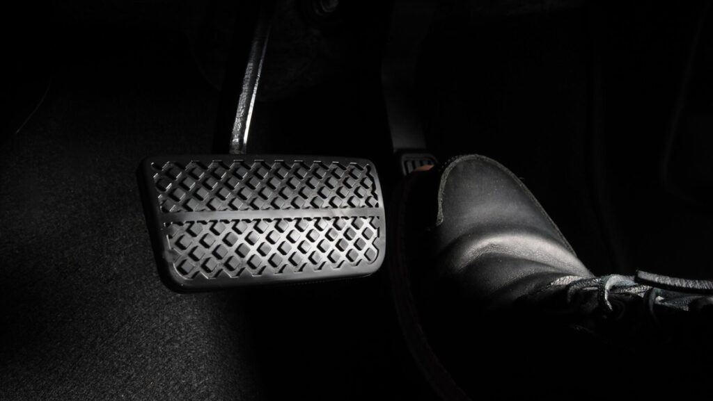 Pied de l'homme et accélérateur et pédale de frein à l'intérieur de la voiture ou du véhicule et de l'espace de copie dont la chaussure en cuir de couleur noire a marché dessus pour accélérer ou contrôler la puissance du rythme de l'automobile.