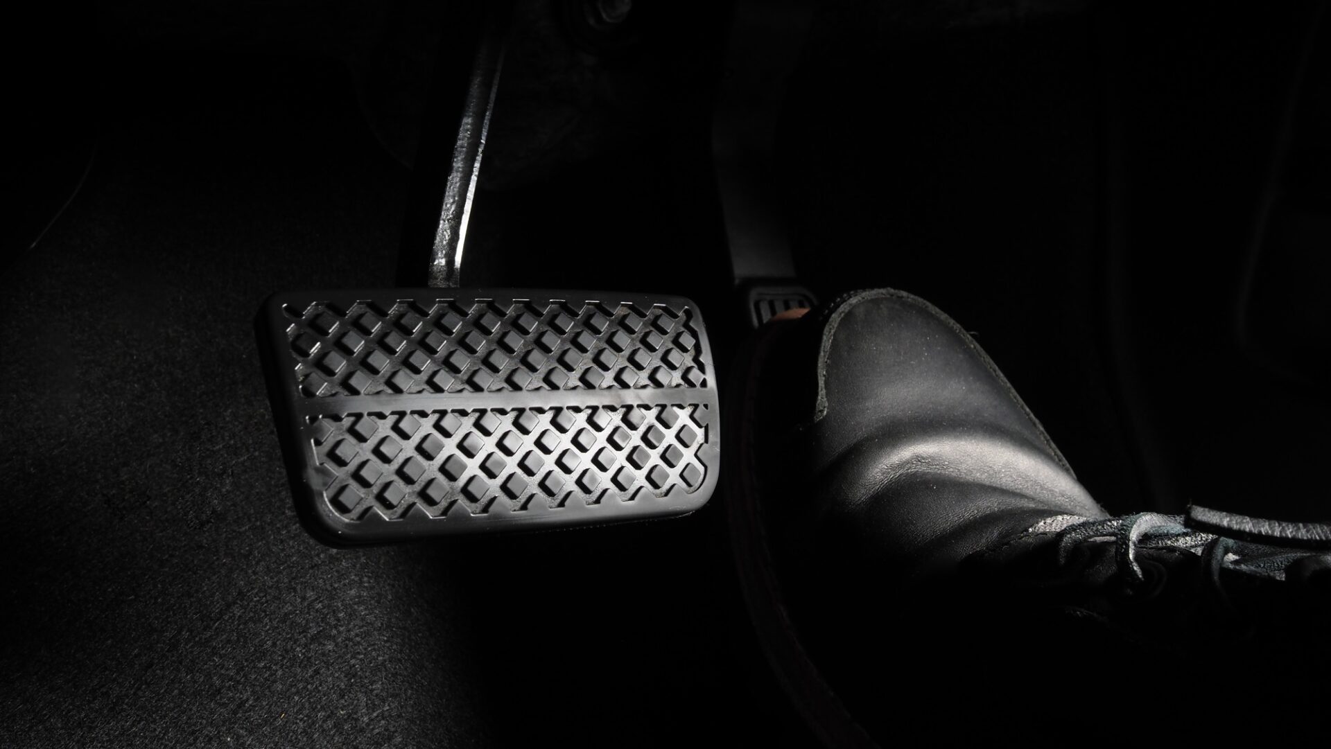 Pied de l'homme et accélérateur et pédale de frein à l'intérieur de la voiture ou du véhicule et de l'espace de copie dont la chaussure en cuir de couleur noire a marché dessus pour accélérer ou contrôler la puissance du rythme de l'automobile.