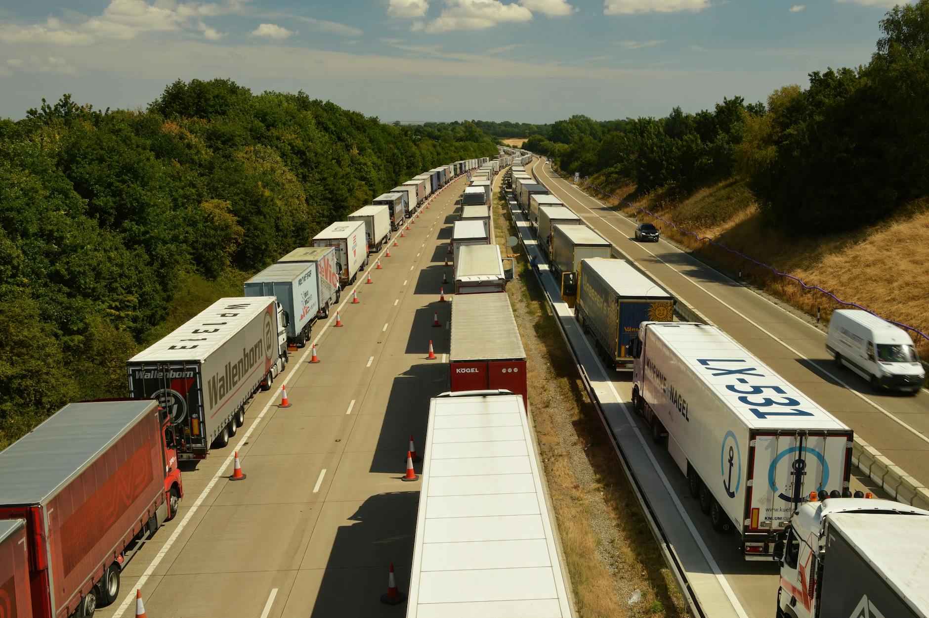 Un plan élevé de camions et de remorques dans la circulation sur une autoroute en Angleterre sous un ciel brillant.