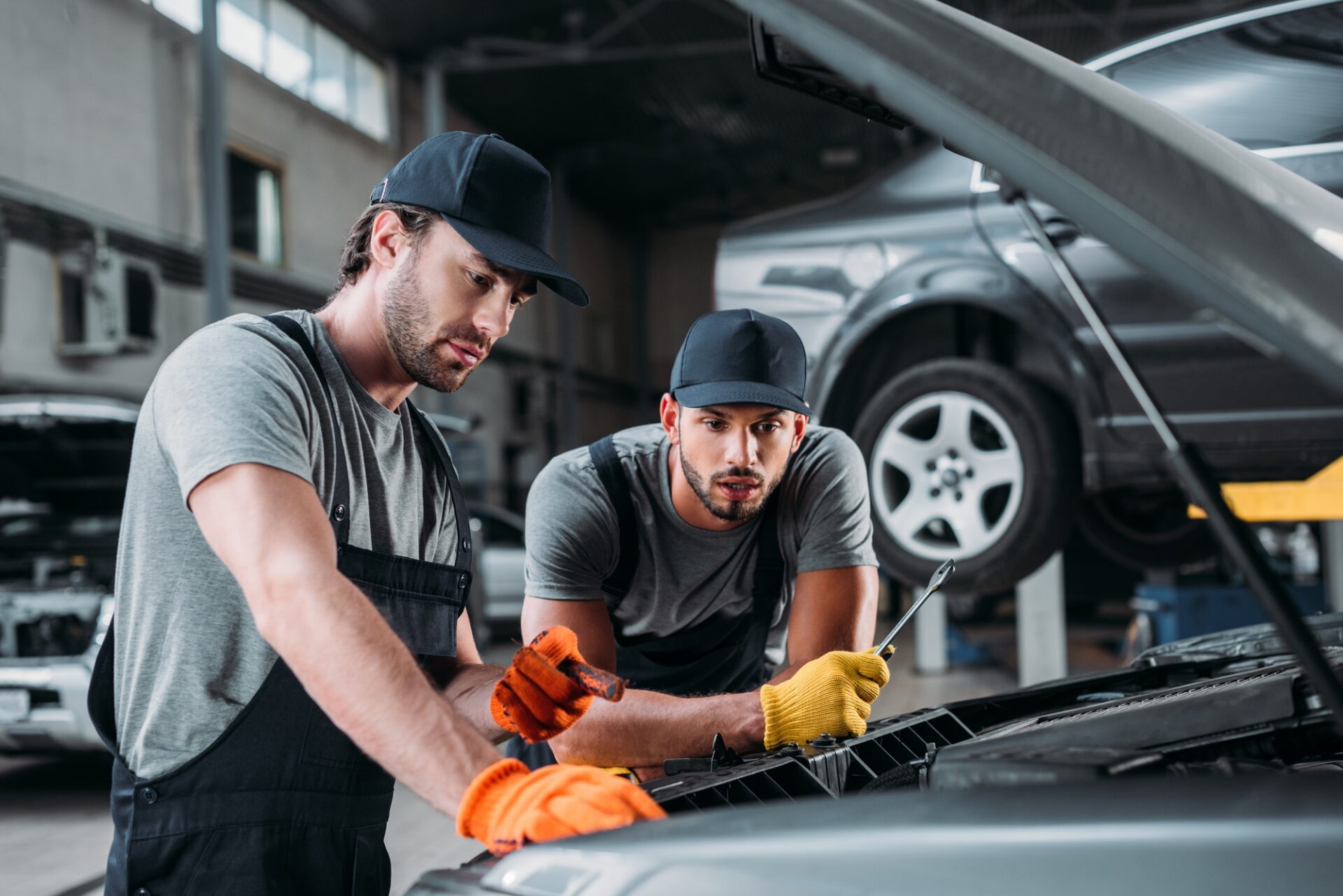 travailleurs manuels professionnels réparant la voiture dans une boutique de mécanicien