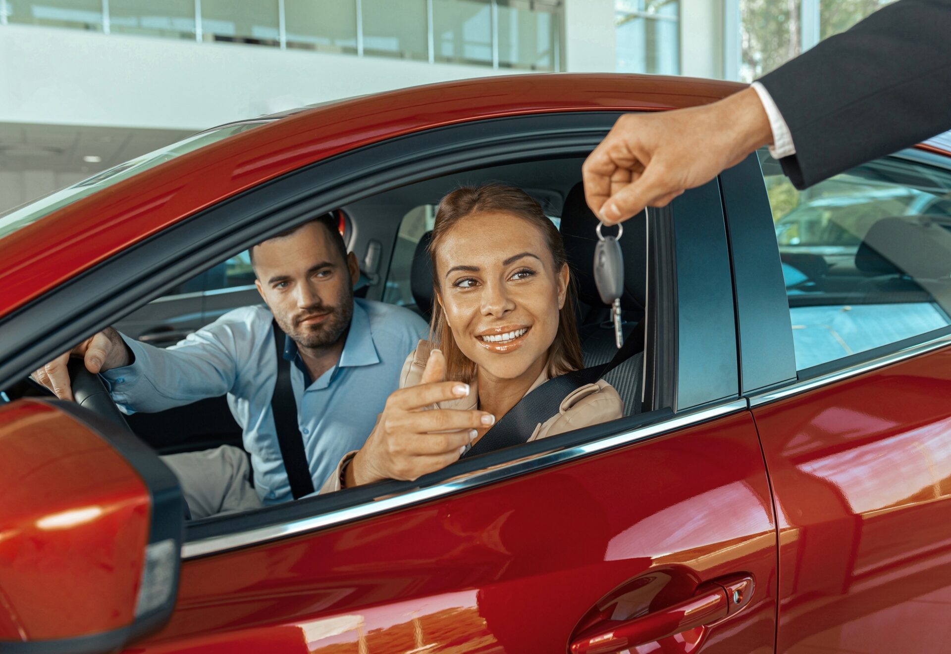 Couple assis à l'intérieur de la voiture neuve et tenant des clés.