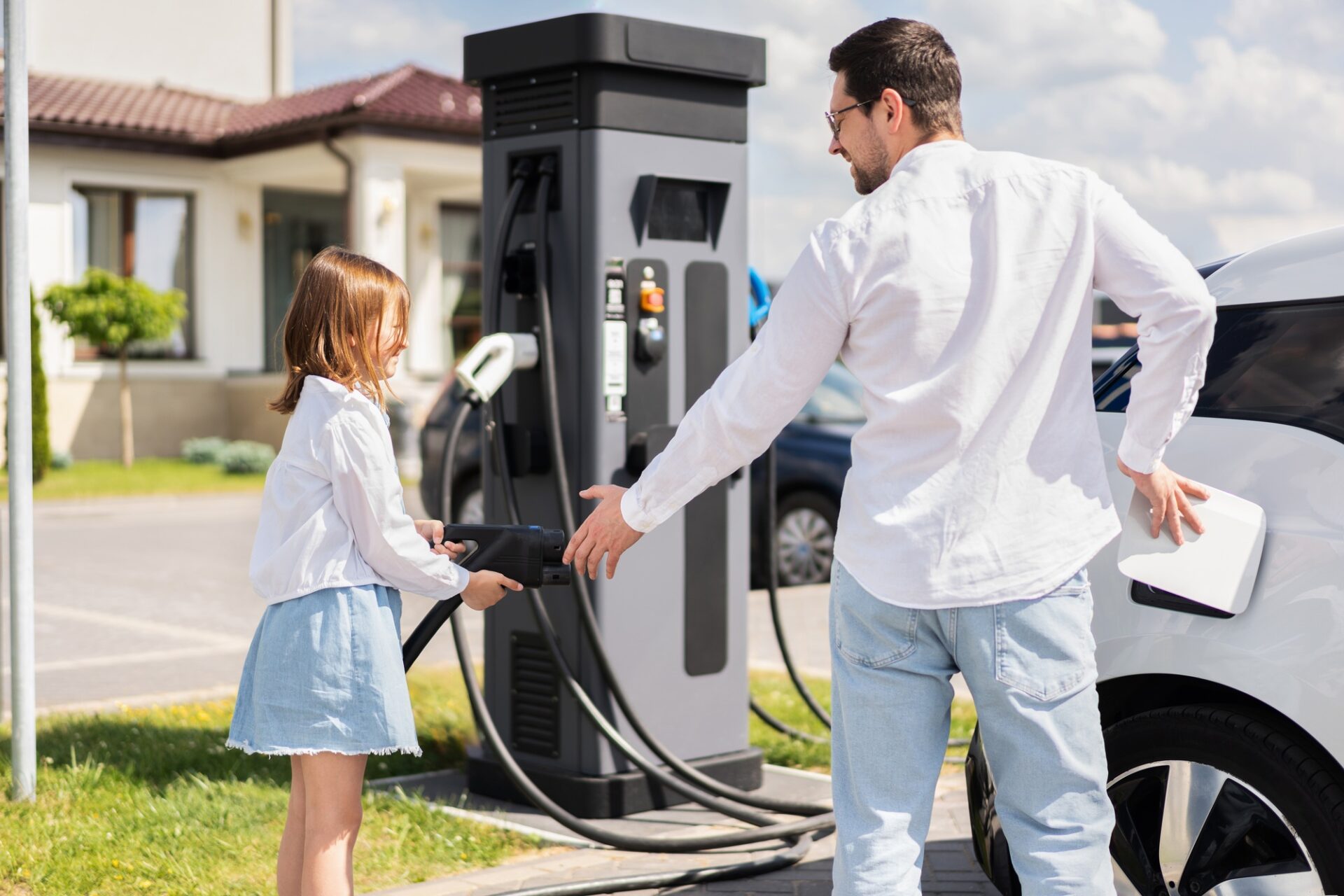 Père et fille facturant une voiture électrique à la gare, démontrant une vie durable et un avenir à énergie propre
