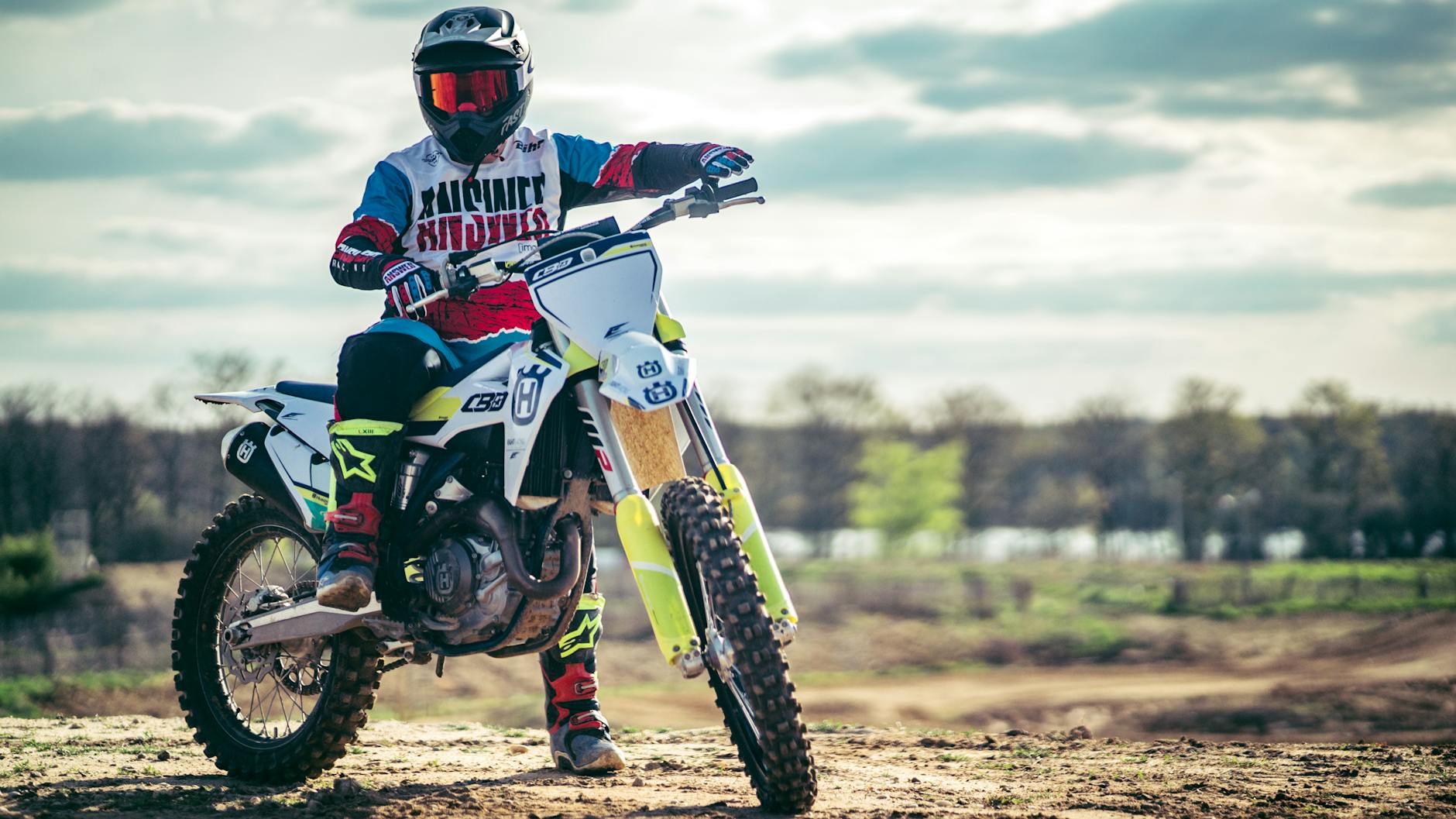 Un pilote de motocross en pleine tenue sur une moto tout-terrain, courant en plein air.