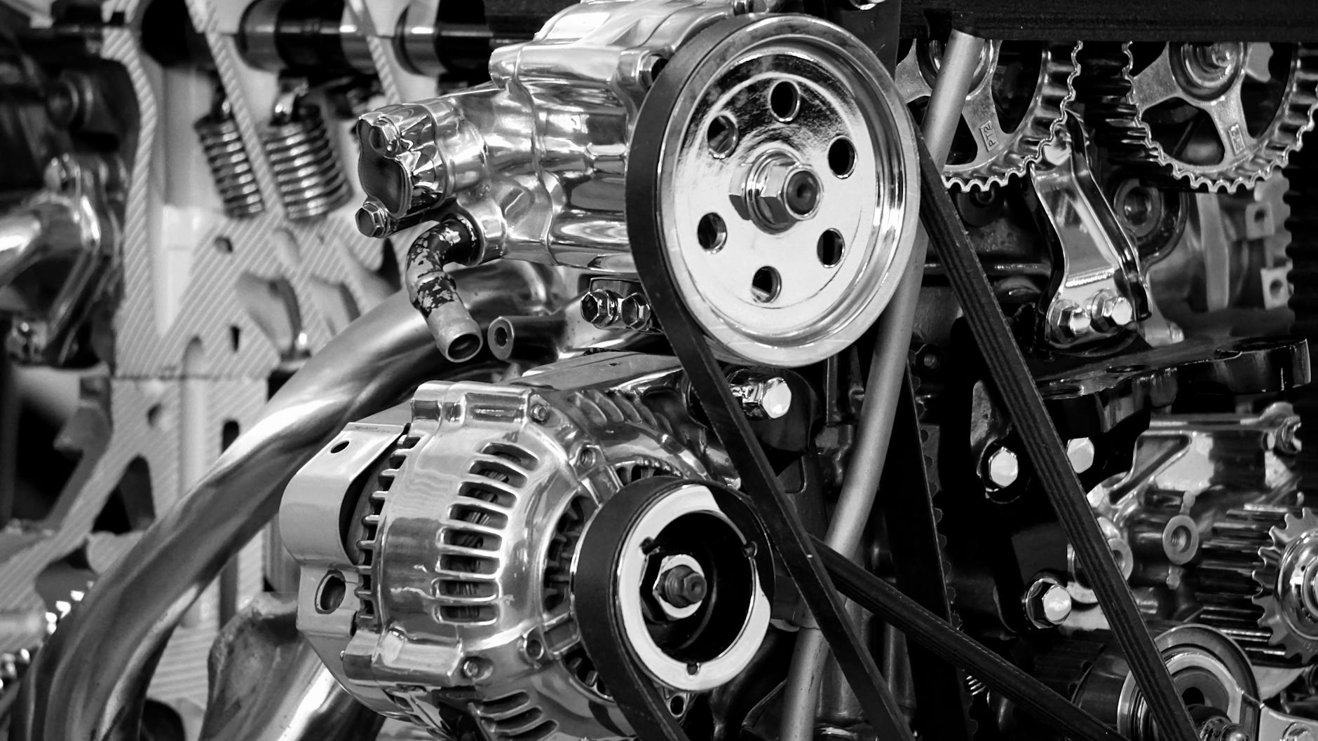 Gros plan d'un moteur de voiture brillant montrant des pièces et des engrenages en métal poli en noir et blanc.