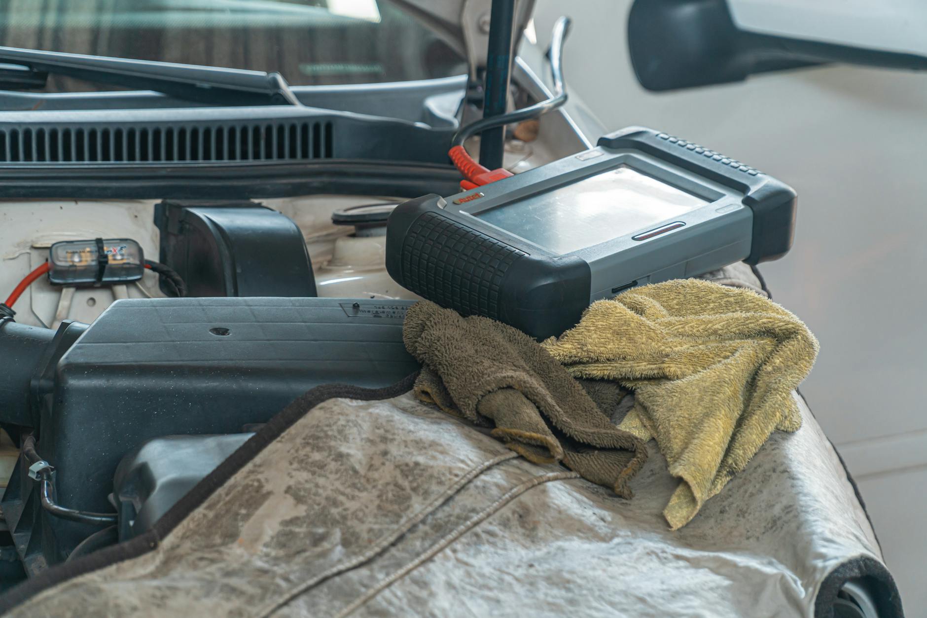 Gros plan de l'outil de diagnostic automobile sur le moteur dans un garage.