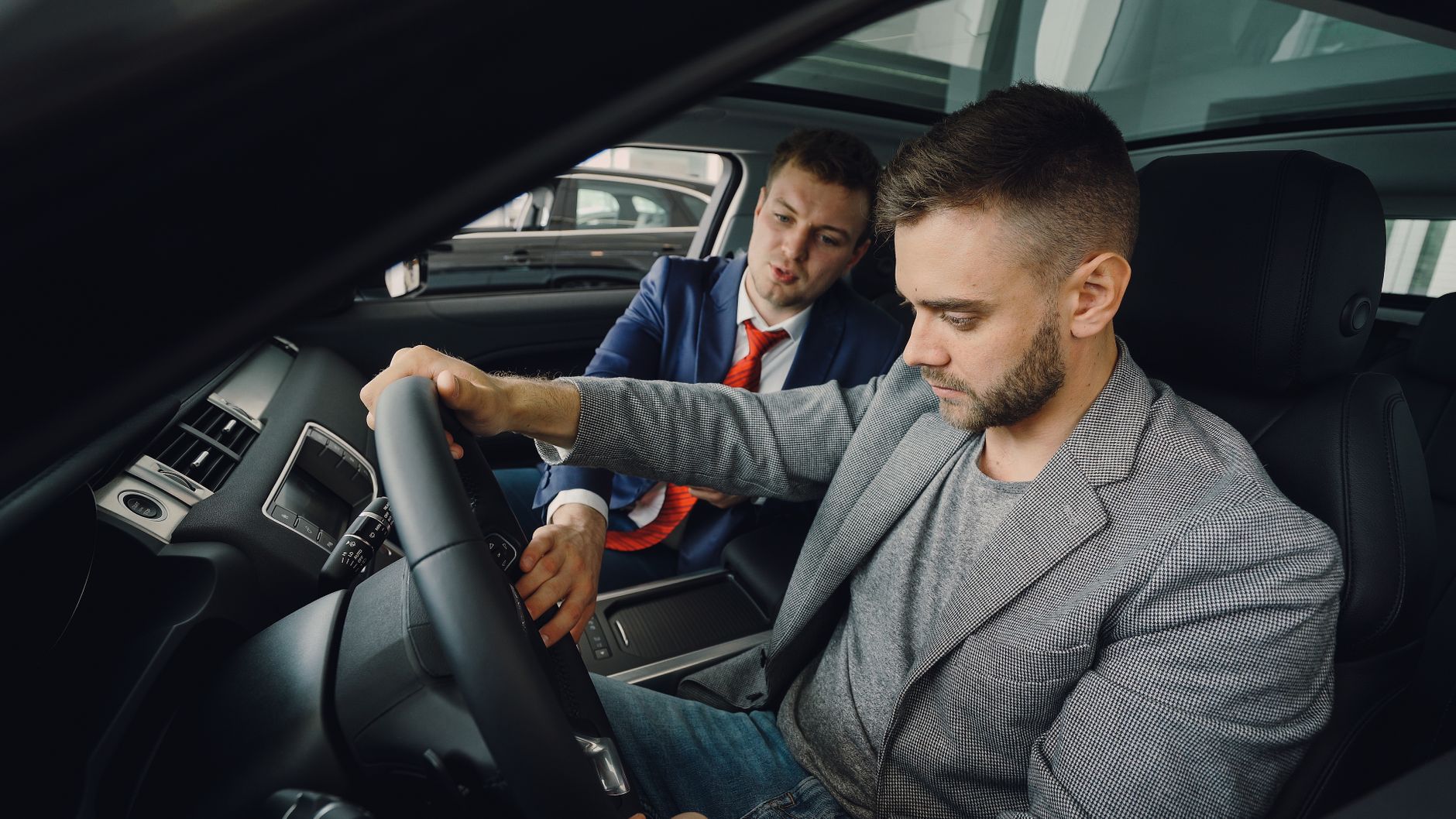 Vendeur démontrant les caractéristiques de la voiture à l'acheteur potentiel dans la salle d'exposition du véhicule.